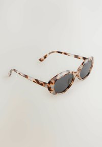 Lunettes de soleil en écaille avec une monture ovale, verres noirs, et finition lisse et brillante. Les branches présentent un design courbe subtil.