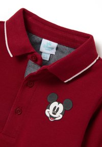 Bordeauxpoloshirt met een wit afgewerkt kraag, voorzien van een Mickey Mouse-ontwerp op de voorkant en knoopsluitingen bij de hals.