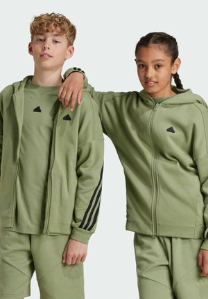 Sudaderas con capucha verdes y pantalones cortos, hechos de tejido suave. Los acentos negros incluyen el logotipo y las franjas. Textura suave, corte relajado.