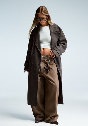 Brown wool overcoat with large lapels, paired with high-waisted brown wide-leg pants and a white crop top. Accessories include a keychain.