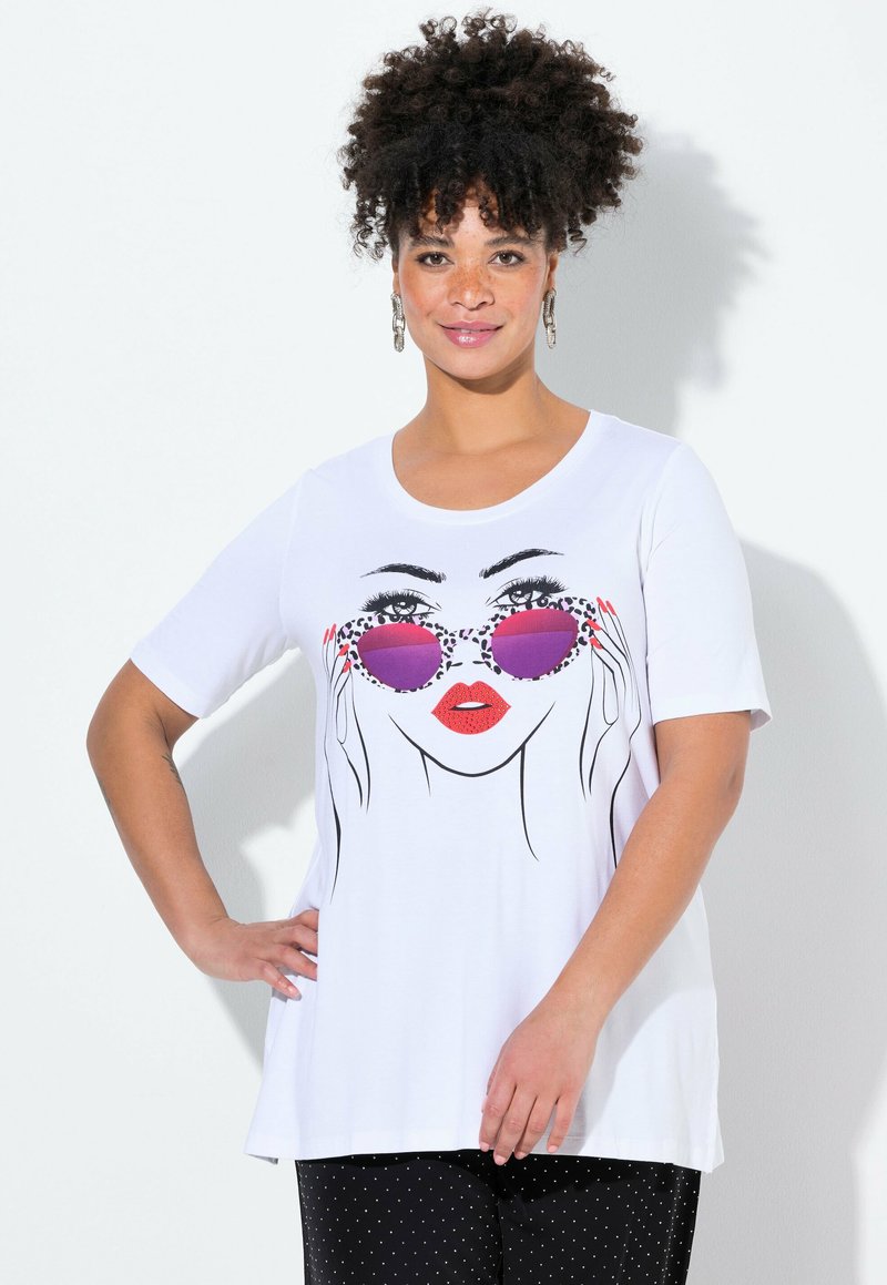 T-shirt blanc à manches courtes ornée d'un dessin au trait noir d'un visage avec des lunettes de soleil violettes et des lèvres rouges. Tissu doux, coupe ample.