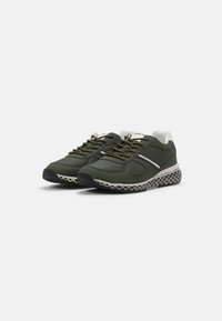 Green athletic shoes with a textured mesh sole, smooth upper, and contrasting white accents. Features laces and a padded collar for comfort.