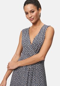 Navy dress with a geometric pattern in cream and beige, featuring a deep V-neck, sleeveless design, and a flared silhouette.