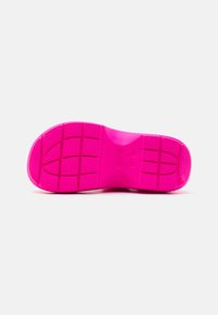 Suola di una scarpa in gomma rosa brillante, dotata di un motivo testurizzato con scanalature orizzontali e verticali per la presa e la trazione.
