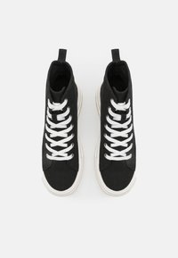 Svarta hightop sneakers i canvas med vita snören, med en strukturerad yta och en gräddfärgad gummisula. Dragflik på varje häl.