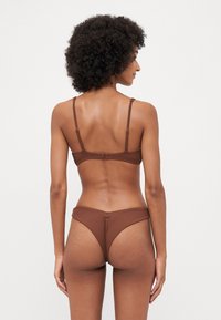 Brown ribbed bikini set with thin straps and a hook closure on the back. The bottoms have a high-cut design and minimal coverage.