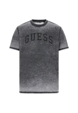 Grijs T-shirt met korte mouwen, voorzien van een vervaagde look, een ronde hals en een zwart bedrukt "GUESS"-logo over de borst.