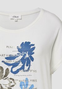 Witte katoenen t-shirt met blauwe bloemenprint en zilveren tekst, met een ronde halslijn en korte mouwen.