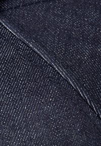 Mørkeblå denimstoff med en teksturert overflate, med et diskret mønster av lyse tråder. Stoffet har en ren, ferdig kant.