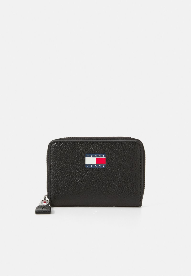 Cartera de cuero negro con un acabado texturizado. Presenta una forma rectangular y un parche de logo colorido de Tommy Jeans en la parte frontal.