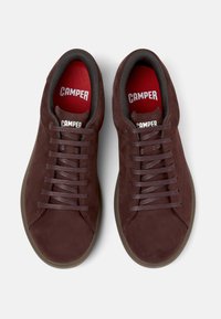 Brown suede sneakers with round toe, textured surface, gray laces, and red insoles featuring "CAMPER" branding. Flat rubber outsole.