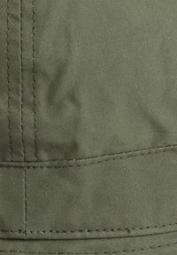 Κοντινό πλάνο ύφασματος ελιάς με ορατές ραφές που σχηματίζουν μια ραφή και διακριτικές πτυχώσεις.