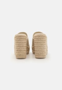 Sandalias de plataforma beige con altos tacones de cuerda trenzada, parte superior de tejido suave, diseño de espalda abierta y punta redonda.