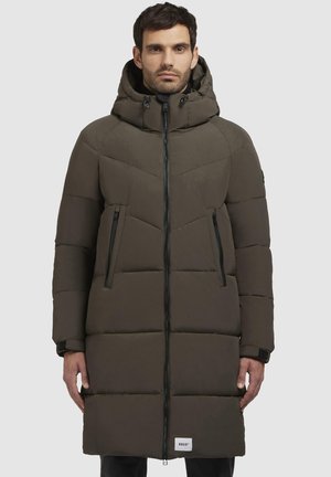 Gevoerde parka in donker olijfgroen, met een capuchon, zigzag-gequilt patroon en twee ritszakken aan de zijkant. Zwarte ritssluiting aan de voorkant.