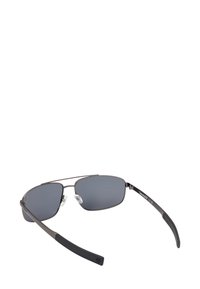 Sluneční brýle s kovovým rámem, tmavými obdélníkovými skly, černými gumovými koncovkami na stranách a nastavitelnými nosními podložkami.