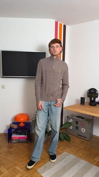 Ανοιχτό καφέ πουλόβερ με πλέξη cable knit και ψηλό γιακά. Συνδυασμένο με ανοιχτόχρωμο μπλε τζιν και μαύρα αθλητικά παπούτσια. Τα αξεσουάρ περιλαμβάνουν τατουάζ.