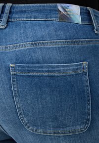 Medium siniset farkut, joissa on sileä pinta, yksi takatasku ja etiketti, jossa lukee "ONLY CARMAKOMA Denim."