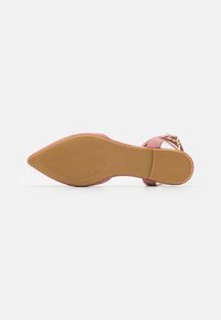 Zapato de tacón alto de ante rosa con puntera puntiaguda, que presenta una suela texturizada y un acento de hebilla dorada en una correa para el tobillo.