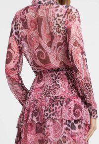 Blusa con stampa floreale e leopardata in tonalità di rosa, con tessuto trasparente, maniche lunghe, colletto e dettaglio arricciato sull'orlo in vita.