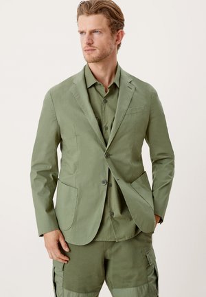 Zestaw marynarki i koszuli w oliwkowym kolorze, dopasowany krój, zapięcie na dwa guziki, kieszenie naszywane oraz teksturowany materiał. Casualowy, nowoczesny design.