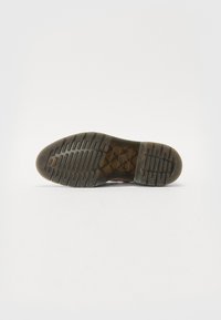 Sola de sapato de borracha castanha com um padrão texturizado e sulcos para tração. Apresenta um logótipo de marca no centro. Bordas suaves.