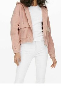 Ljusrosa kordjacka med huva, frontdragkedja och elastisk midja. Har två framfickor och åtsittande mudd. Bärs över en vit skjorta.