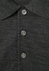 Polo de culoare gri închis, cu un model de tricot texturat, guler și cinci butoane metalice pe față.