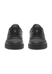 Mustad mustajad, millel on siledast nahast ülemine osa, ümmargune varvas, nööbid ja tekstuuriga kummine tallad ning kontrastsete logode detailid keelel.