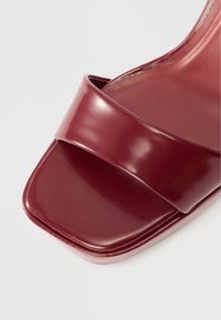 Sandalie burgundii cu vârful deschis, cu un finisaj lucios, având o curea lată peste partea de sus și un design pătrat, robust pentru vârf. Textură netedă.