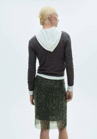 Grijze lange mouwen hoodie met witte capuchon, gecombineerd met een doorzichtige, groen slangenpatroon rok. Soepele textuur en aansluitend ontwerp.