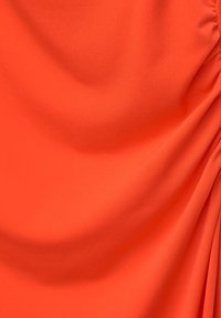 Tissu orange vif avec une texture lisse, présentant des détails de drapés et de fronces subtils, créant des plis et des contours dynamiques.