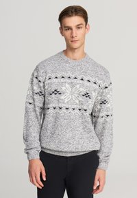 Maglione a maglia grigio e bianco con un motivo di fiocchi di neve in nero, dotato di polsini e fondo a costine. Collo a giro, vestibilità rilassata, tessuto testurizzato.