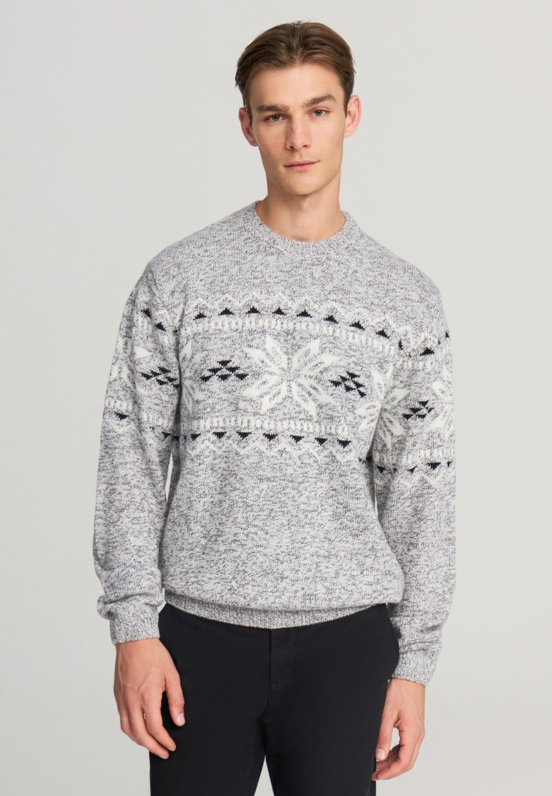 Maglione a maglia grigio e bianco con un motivo di fiocchi di neve in nero, dotato di polsini e fondo a costine. Collo a giro, vestibilità rilassata, tessuto testurizzato.