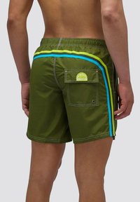 Pantaloni da bagno verdi con strisce blu e giallo neon, vita elastica e tasca posteriore con patch logo. Tessuto liscio e leggero.