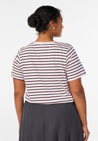 Lühikeste varrukatega triibuline t-särk, millel on heleroosad ja tumedad pruunid triibud, ümmargune kaelus ja mugav lõige. Kandmiseks volditud seelikuga.