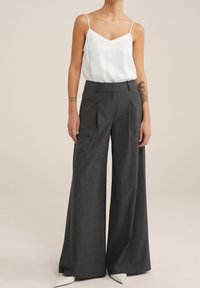 Gray wide-leg trousers with front pleats, paired with a white spaghetti strap top. Smooth fabric with a tailored fit and minimal details.