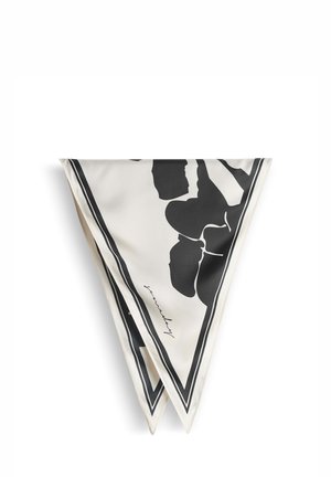 Foulard carré en soie plié en triangle, présentant des motifs floraux noirs et une signature sur un fond blanc avec une bordure noire.