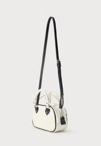 Geantă albă cu margini negre, formă rotunjită, două mânere superioare și o curea reglabilă. Finisaj texturat cu cusături în contrast și accente în formă de inimă.