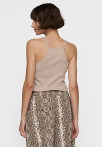 Beige geribbelde tanktop met dunne bandjes, gecombineerd met een rok met een bruin en crèmekleurig slangenpatroon. Zichtbare textuur en ontwerpelementen.