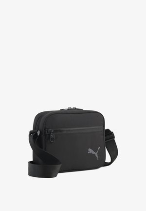 Schwarze rechteckige Umhängetasche mit vorderer Reißverschlusstasche und verstellbarem Riemen, mit kleinem Puma-Logo auf der Vorderseite.