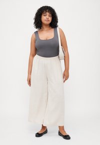 Grey bodysuit with a square neckline, paired with loose, beige linen wide-leg pants and black ballet flats. Simple handbag completes the look.