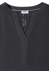 Col de chemise en lin gris foncé avec une fente en V et un bord cousu, avec des étiquettes de la marque CECIL et de la composition en lin à l'intérieur du col.