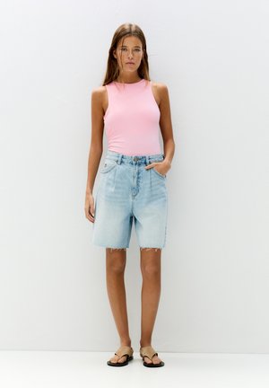 Body roz fără mâneci, pantaloni scurți din denim bleu deschis cu tiv destrămat și sandale bej. Modelul stă în fața unui fundal simplu.