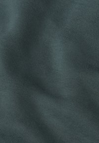 Mörkgrönt tyg med en mjuk, slät textur och ett subtilt, jämnt vävmönster. Lätt reflekterande under vissa vinklar.