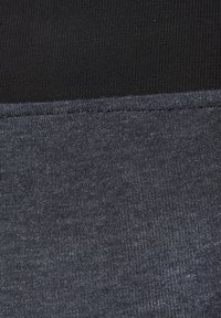 Čierne a tmavošedé legíny s rebrovanou textúrou na vrchu a hladkým, melírovaným povrchom na spodnej časti. Viditeľné švy.