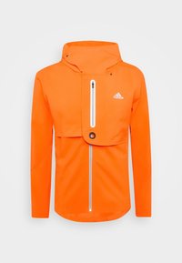 Giacca impermeabile arancione da uomo con colletto alto, chiusura frontale con zip e tasca a pattina. Presenta una zip e un logo bianco in evidenza.