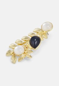 Gold-toned brooch with leaf design, featuring two round white stones and one teardrop black stone as accents. Smooth and textured finishes.