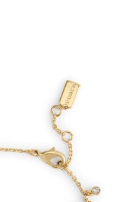 Gold-toned metal bracelet features a chain design, a lobster clasp, and a rectangular tag marked with “COACH.” Includes a small sparkling detail.