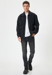 Svart denimjacka med elastiska ärmmuddar, två framfickor och dragkedja. Matchas med mörkgrå jeans och svarta sneakers.
