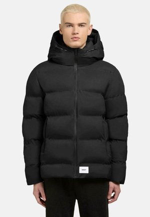 Black puffer jacket featuring a zip front, oversized hood, and a square logo patch on the hem. Made of smooth, insulated material.